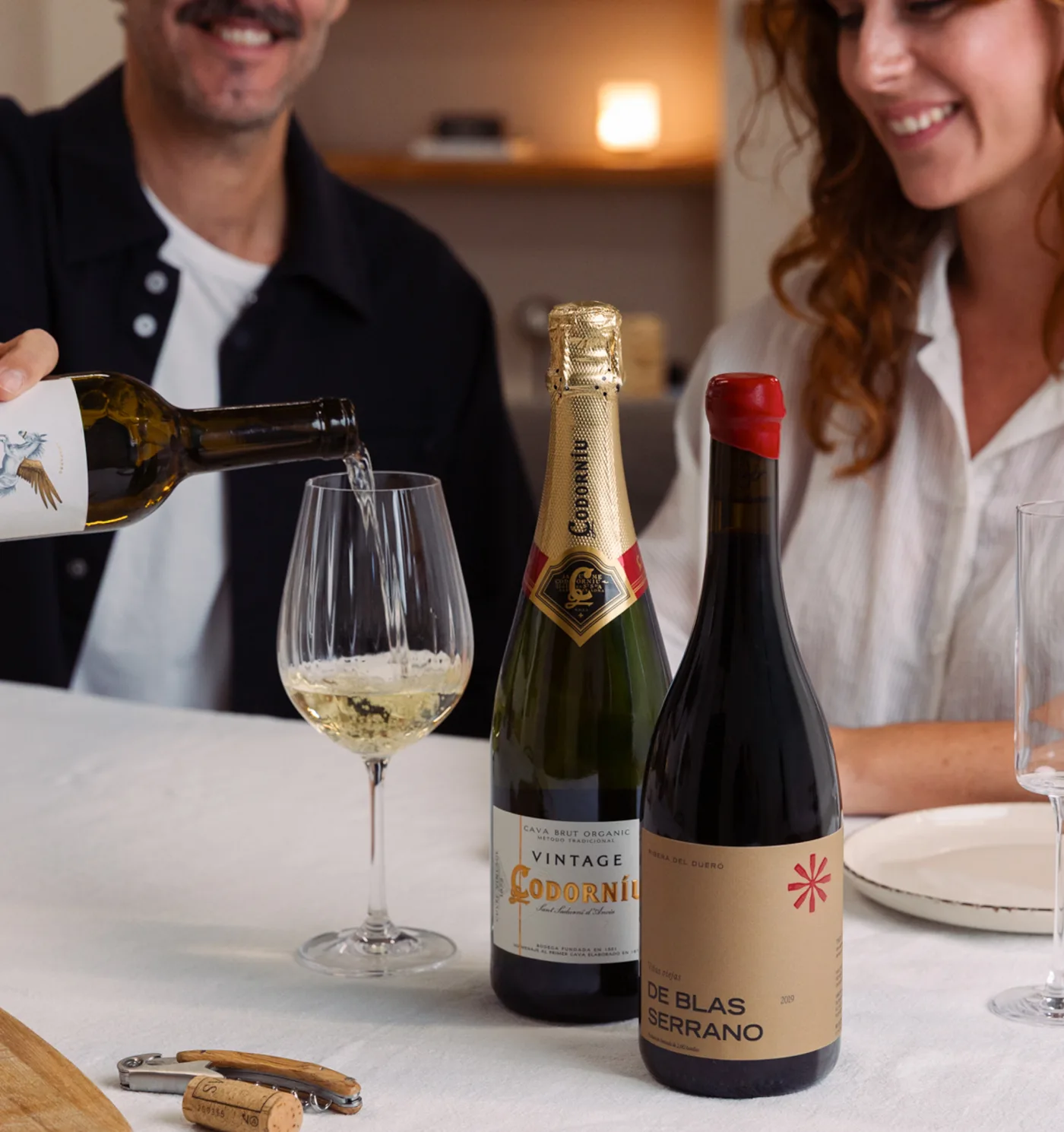 Paar stößt am Tisch mit Weißwein, Cava und Rotwein an