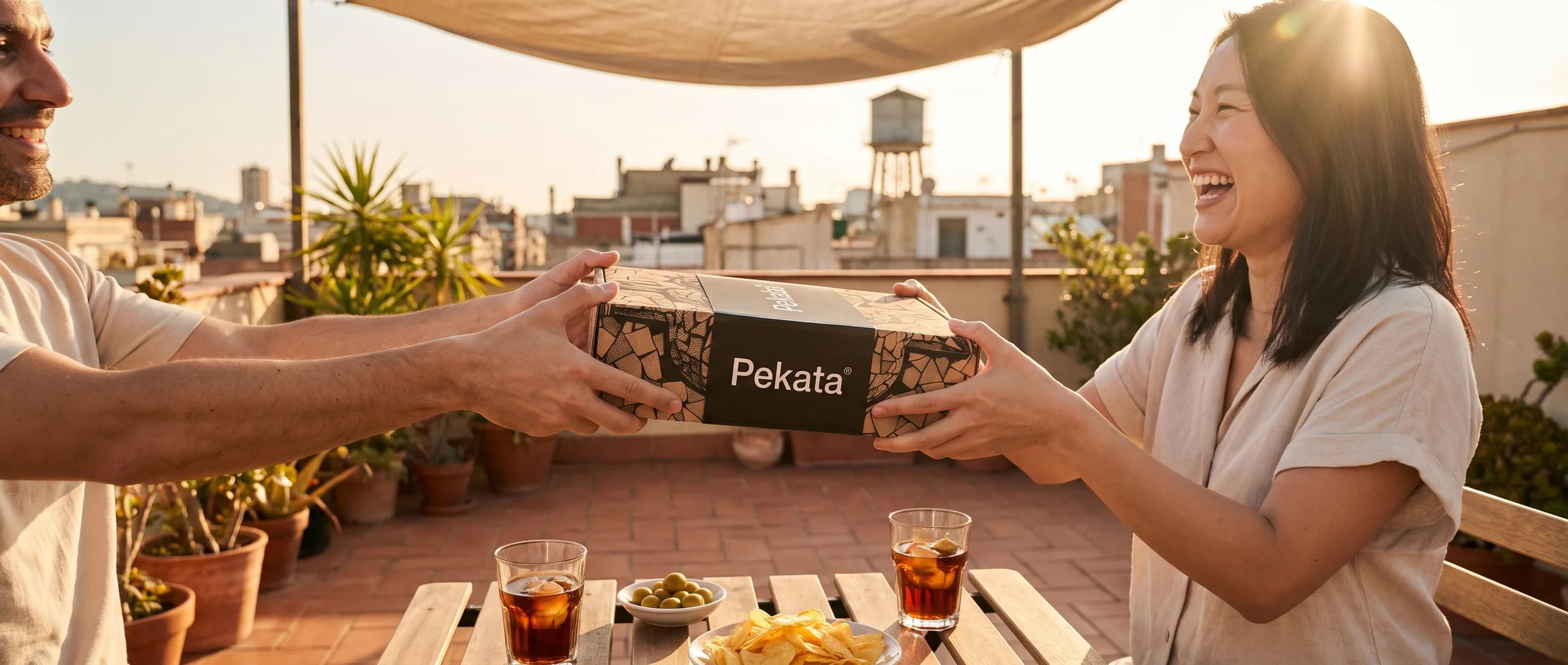 Zwei Freunde übergeben eine Pekata-Box auf einer Dachterrasse in Barcelona